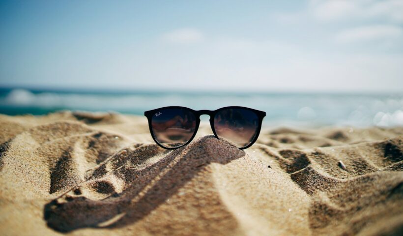 black Ray-Ban Wayfarer sunglasses on beach sand